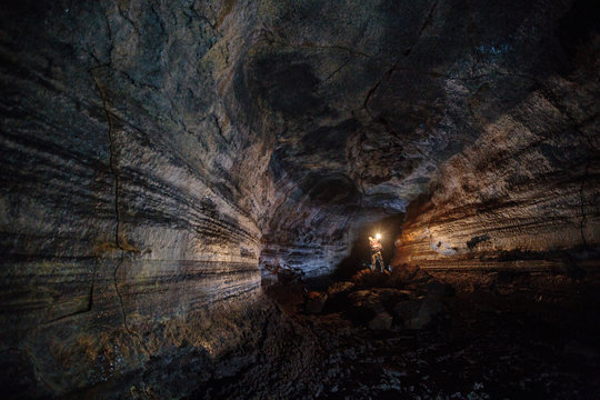 A male caver holding a propane lantern while exploring the 13,042 foot long Ape Cave near Mount St. Helens in the Gifford Pinchot National Forest of western Washington State. The cave is the third longest known lava tube in North America. The cave is open year round and has a easier, shorter lower cave section and a slightly more physical and longer upper cave section.