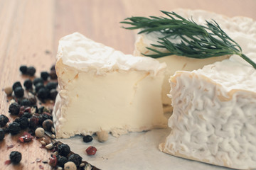 Camembert with spices and thyme on a rustic wooden table.