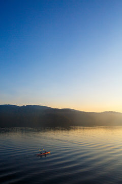 Two tandem kayakers paddle into the early morning light near Harney Channel while on a 3-day sea kayaking trip in the San Juan Islands. The photo was taken from Blind Island, a small 3 acre state park near Shaw Island that offers camping opportunities to human and wind-powered boats.
