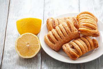lemon puff dessert on a white plate with sliced lemon on a wooden table
