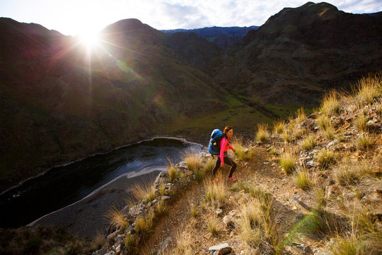 A female backpacker hiking switchbacks near the 400-foot Suicide Point along the scenic Snake River National Recreation Trail (#102) in Hells Canyon along the Oregon-Idaho border. The canyon is the deepest river gorge in North America with more than a mile of vertical elevation between the river floor and nearby peaks in the Seven Devil Mountains.