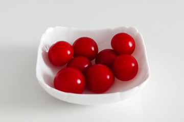 Fresh cherry tomatoes in a white plate, on a white background, White and Red Concept
