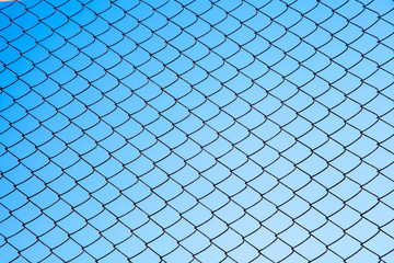 Fototapeta premium blue sky through a metal grid. fence fence.