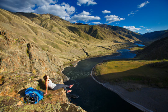 A female backpacker at the 400-foot Suicide Point along the scenic Snake River National Recreation Trail (#102) in Hells Canyon along the Oregon-Idaho border. The canyon is the deepest river gorge in North America with more than a mile of vertical elevation between the river floor and nearby peaks in the Seven Devil Mountains.