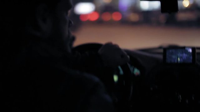 A man gets into the car and turns on the navigator on the smartphone
