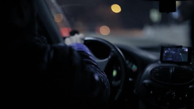 A man gets into the car and turns on the navigator on the smartphone