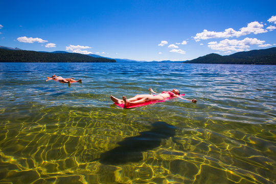Two women escape the summer heat by floating on inflatable Thermarest sleeping pads at a swimming area near Reeder Bay Campground on the west end of the pristine and beautiful Priest Lake in north Idaho.