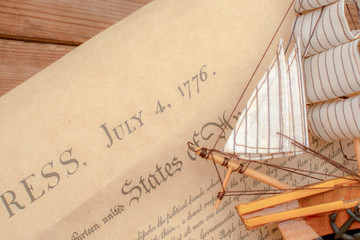 Ship made of wood and fabric handmade on the background of an excerpt from a copy of the document of 1776 on the signing of the independence of America