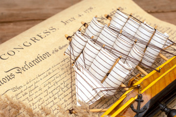 Fototapeta na wymiar Ship made of wood and fabric handmade on the background of an excerpt from a copy of the document of 1776 on the signing of the independence of America