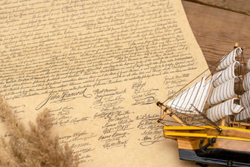 Ship made of wood and fabric handmade on the background of an excerpt from a copy of the document of 1776 on the signing of the independence of America