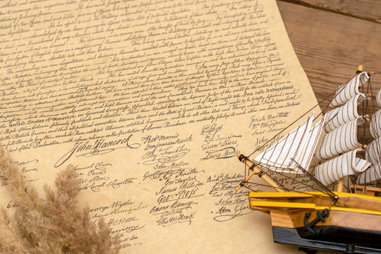 Ship made of wood and fabric handmade on the background of an excerpt from a copy of the document of 1776 on the signing of the independence of America