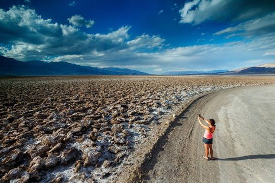 A woman takes a picture with her phone at the Devil's Golf Course in Death Valley National Park, California, in winter.