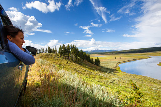 A Woman Leans Out Of The Window Of A Subaru While Looking Out Over The Yellowstone River In Yellowstone National Park.