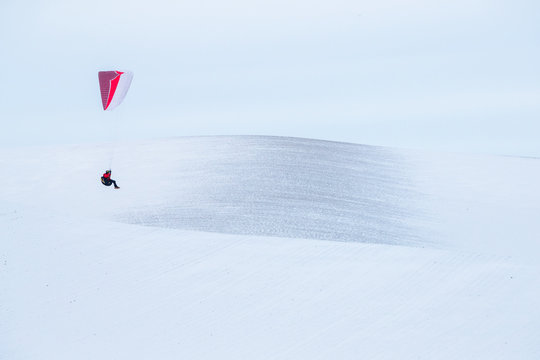 Male paraglider over snow covered hills of Palouse, USA
