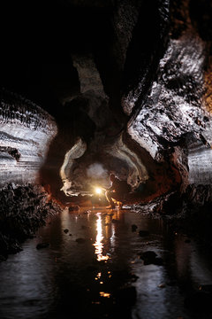 A male caver holding a propane lantern while exploring the 13,042 foot long Ape Cave near Mount St. Helens in the Gifford Pinchot National Forest of western Washington State. In the winter and spring the cave seeps continuously causing light to glisten off the walls and occasional puddles. The cave is the third longest known lava tube in North America. The cave is open year round and has a easier, shorter lower cave section and a slightly more physical and longer upper cave section.