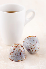 Luxury handcrafted bonbons with cup of coffee espresso on beige marble background