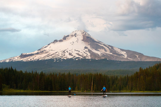 A man and woman stand up paddleboard at Trillium Lake, a popular recreation lake near the base of Mount Hood, Oregon.