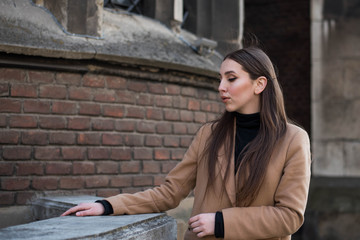 Young beautiful woman with long brown hair in sunglasses on a walk on a cloudy day. Fashionable sexy girl. Street fashion look. Cute student.