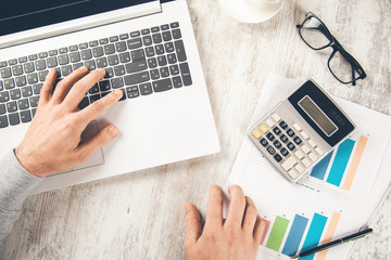 man hand calculator with graph on computer on desk