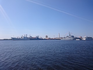 Ships on the water are in the port of Kronstadt, a clear day.