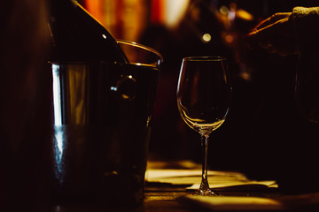 The illuminated glass is on the table next to the bottles of wine in a bucket for cooling. Low key