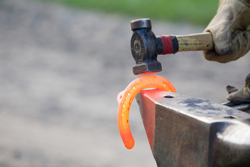 Hufschmied bei der Arbeit, glühendes Eisen wird in Form gebracht mit dem Hammer auf dem Ambos...