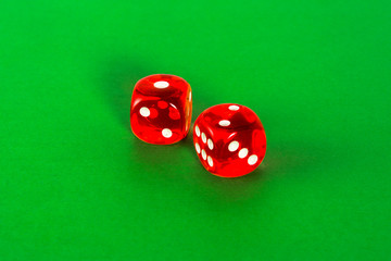 Red transparent dice for gambling on green background.