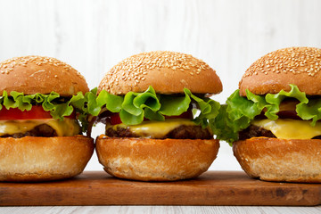 Homemade cheeseburgers on rustic wooden board, side view. Close-up.