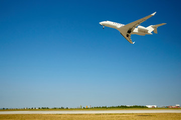 White plane takes off. Blue sky. Free space. Flight over the field and the airport. - 262091461