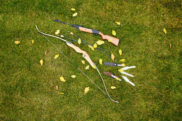 firing weapons: longbow, arrows, shotgun, throwing knives lie on green grass - 262092051
