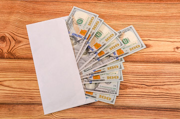 white envelope with dollars on a wooden background. Close-up.