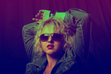 Portrait of a young elegant girl with glasses in neon light. Beautiful blond woman with red lips. Photo stylized toning.