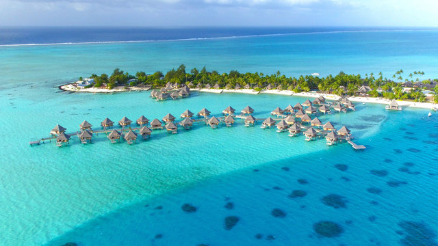 DRONE: Stunning view of the wooden overwater villas above the turquoise sea.