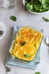 Potato casserole with fish and cheese on a light grey background.