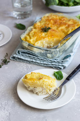 Potato casserole with fish and cheese on a light grey background.
