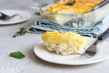 Potato casserole with fish and cheese on a light grey background.
