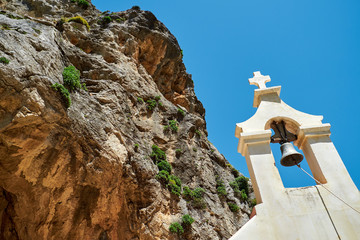 Bell tower of the church in the mountains of Greece. Bottom-up view. High cliff. - 262094272