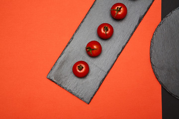 Ripe cherry tomatoes composed on black slate boards on colorful background