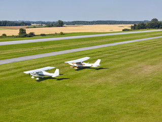 two white pleasure planes on a bright sunny day on the runway of the airfield against the background of the field - 262095698
