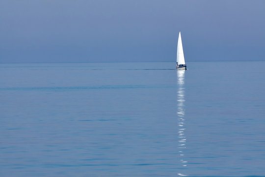 White sailing yacht in the blue sea on the horizon. Seascape. Minimalism.