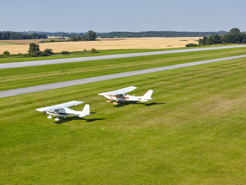 two white pleasure planes on a bright sunny day on the runway of the airfield against the background of the field