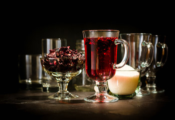 Transparent glass Cup with hot red tea from hibiscus or hibiscus. Glassware and dry petals with sugar.