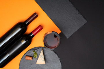 Geometry composition of blue cheese with prosciutto slices on black slate board with bottle of wine...