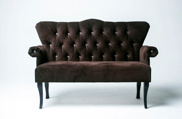 Velvet classic sofa on a light background. Brown sofa with wooden legs