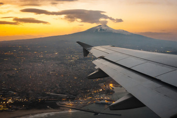 Mount Etna on sunset. Airplane view of Etna with the coast of the city of Catania and his port.