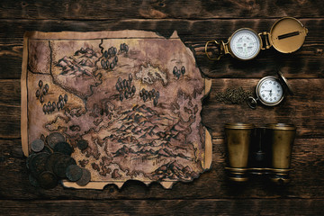 Old map, compass, binoculars and a pocket watch on a adventurer table background. Treasure hunt...