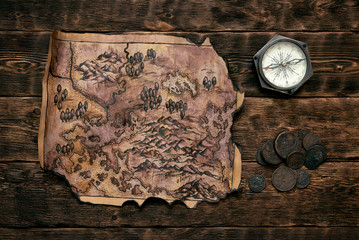 Old map and compass on a adventurer table background. Treasure hunt concept.