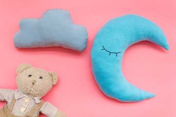 Moon pillow, clouds and teddy bear for put newborn in bed on pink background top view