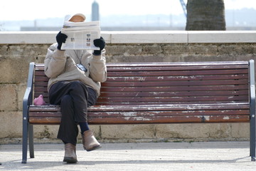 Anziano signore seduto sulla panchina mentre legge un giornale