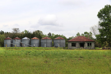 Six abandonded grain silos and an empty wooden shack sit next to a stretch of railroad track in...